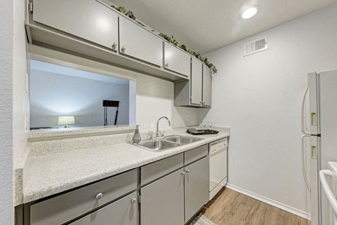 A kitchen with a white counter top and grey cabinets.