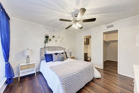A bedroom with a bed, nightstand, and a ceiling fan.