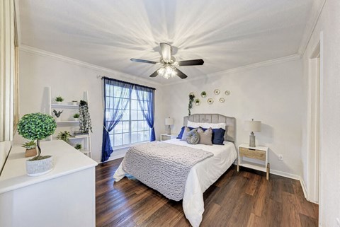 A bedroom with a bed, nightstand, and a ceiling fan.