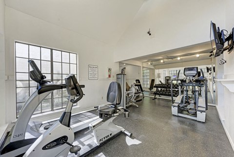 A gym with a treadmill, elliptical machines, and other exercise equipment.