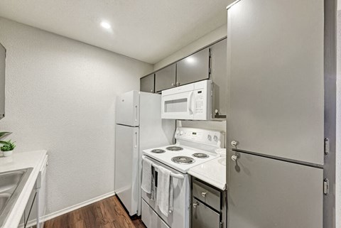 A small kitchen with white appliances and a white counter.