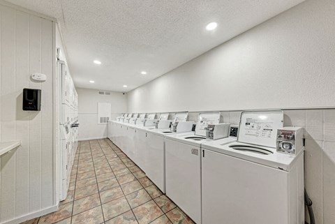 A row of white washing machines in a laundry room.
