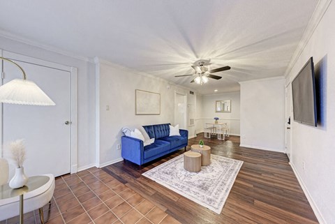 A living room with a blue couch and a ceiling fan.