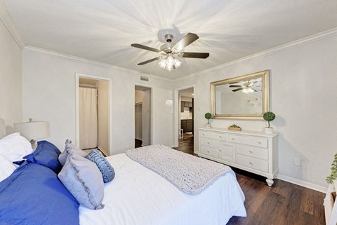A bedroom with a bed, dresser, mirror, and ceiling fan.