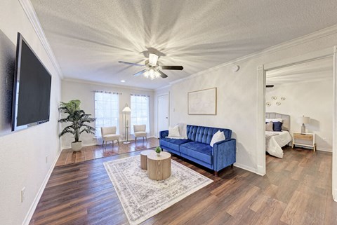 A living room with a blue couch and a television on the wall.