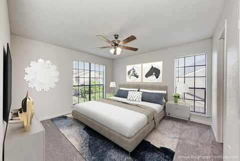 A bedroom with a large bed, a ceiling fan, and a window overlooking a balcony.