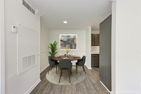 A dining room with a table set for two and a plant in the corner.