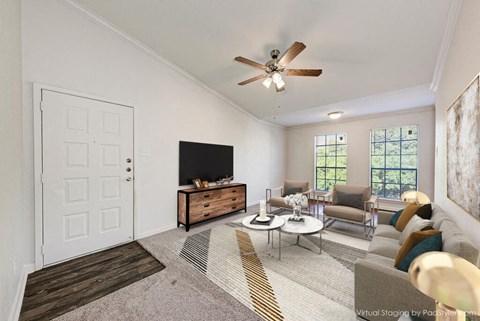 A living room with a white door, a brown rug, a white ceiling fan, and a brown couch.