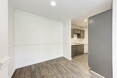 A kitchen area with a white wall and a wooden floor.