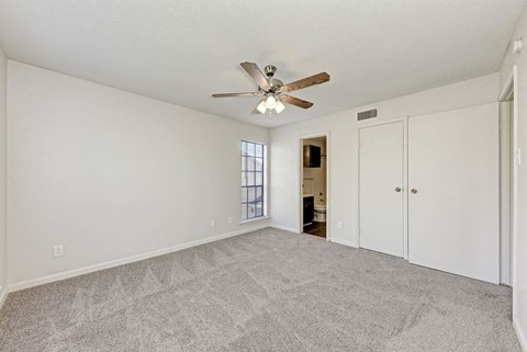 A room with a ceiling fan and carpeted floor.