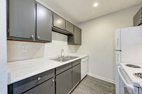 A kitchen with a white refrigerator, sink, and cabinets.