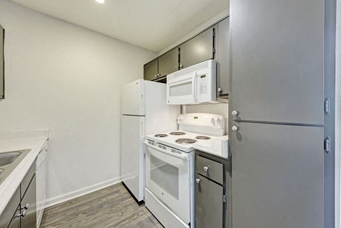 A kitchen with a white fridge, white oven, and white microwave.