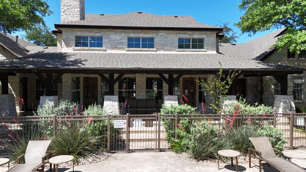 A house with a stone facade and a covered patio with chairs.