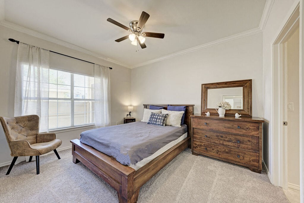 A bedroom with a bed, dresser, and chair.