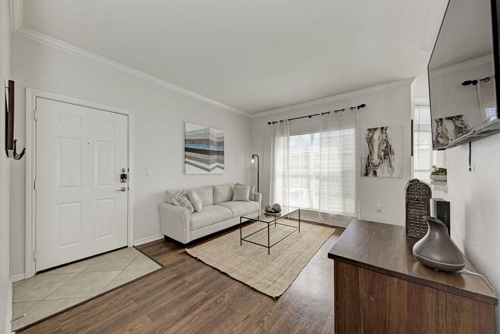 A white door is on the left of a room with a couch and a table.