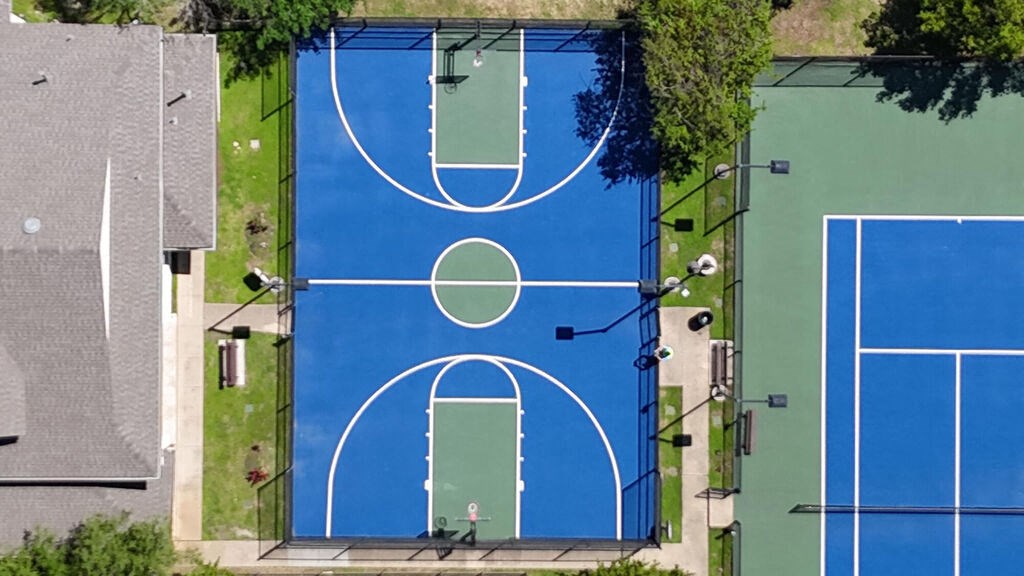 An aerial view of a basketball court surrounded by trees and a building.