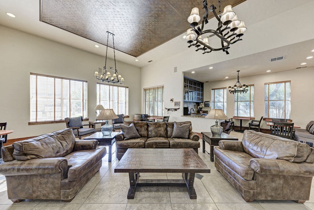 A large, well-lit living room with a variety of seating options and a chandelier.