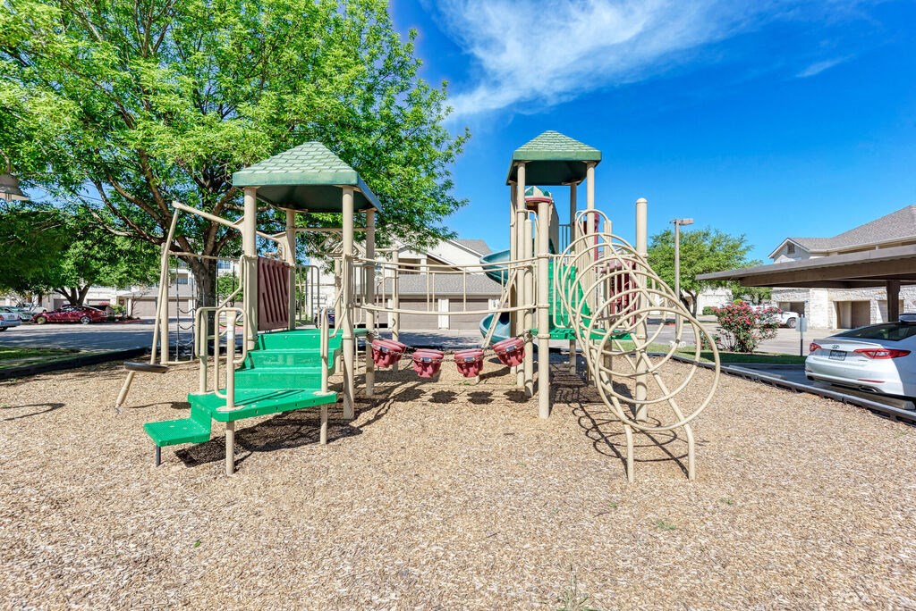 A playground with a green slide and a wooden structure.
