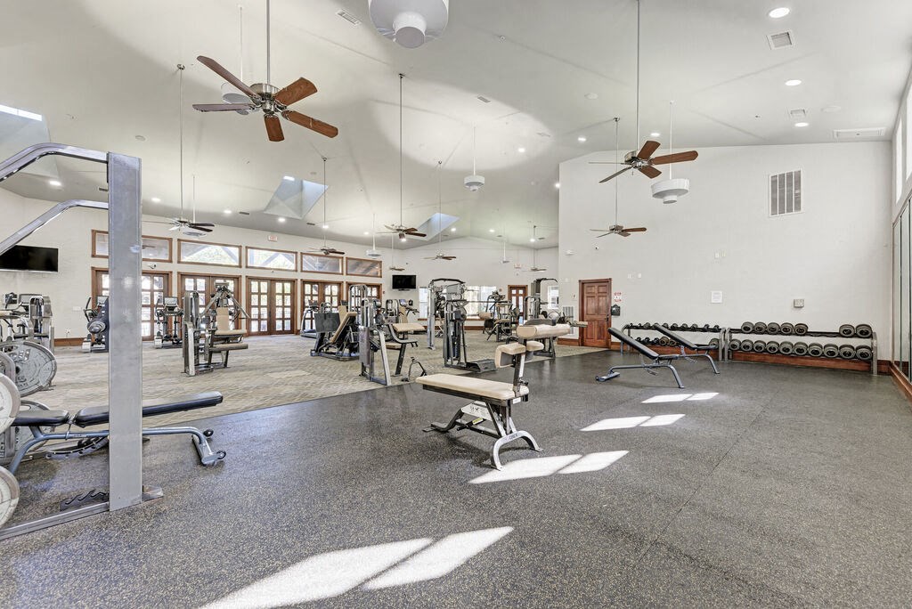 A spacious gym with a variety of equipment and a bench for resting.