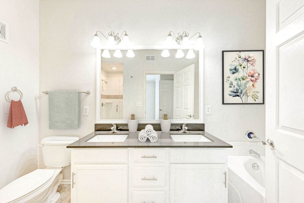 A bathroom with a white toilet, sink, and a large mirror.