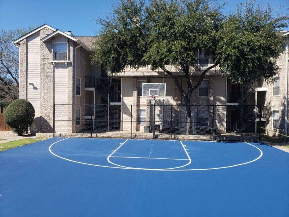 A basketball court in front of a residential building.