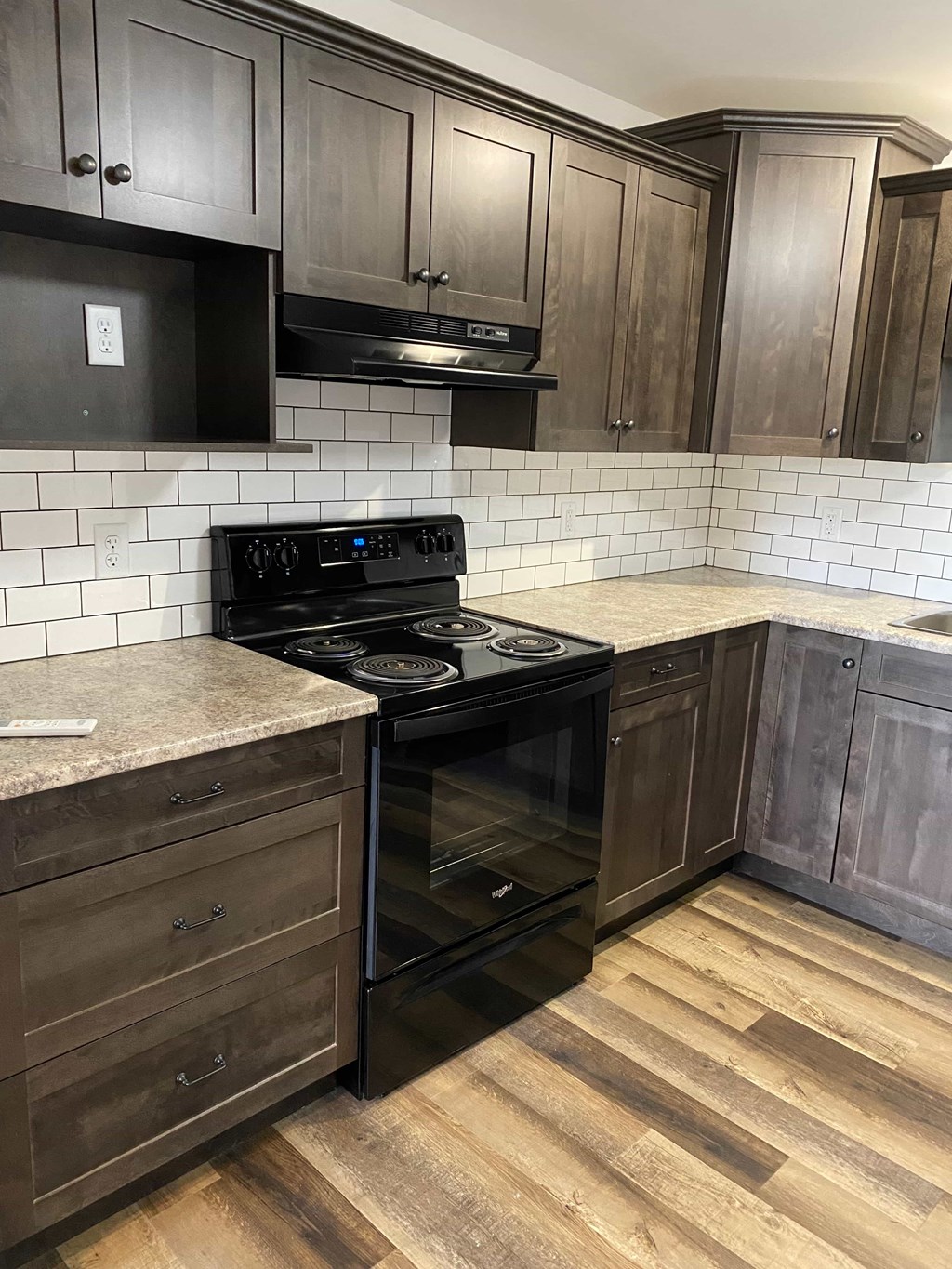 A kitchen with dark wood cabinets and a black stove top oven.