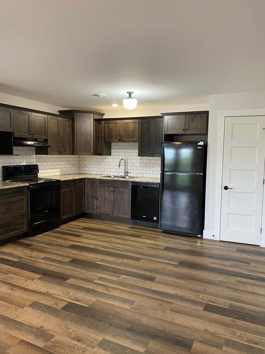 A kitchen with wooden floors and black appliances.
