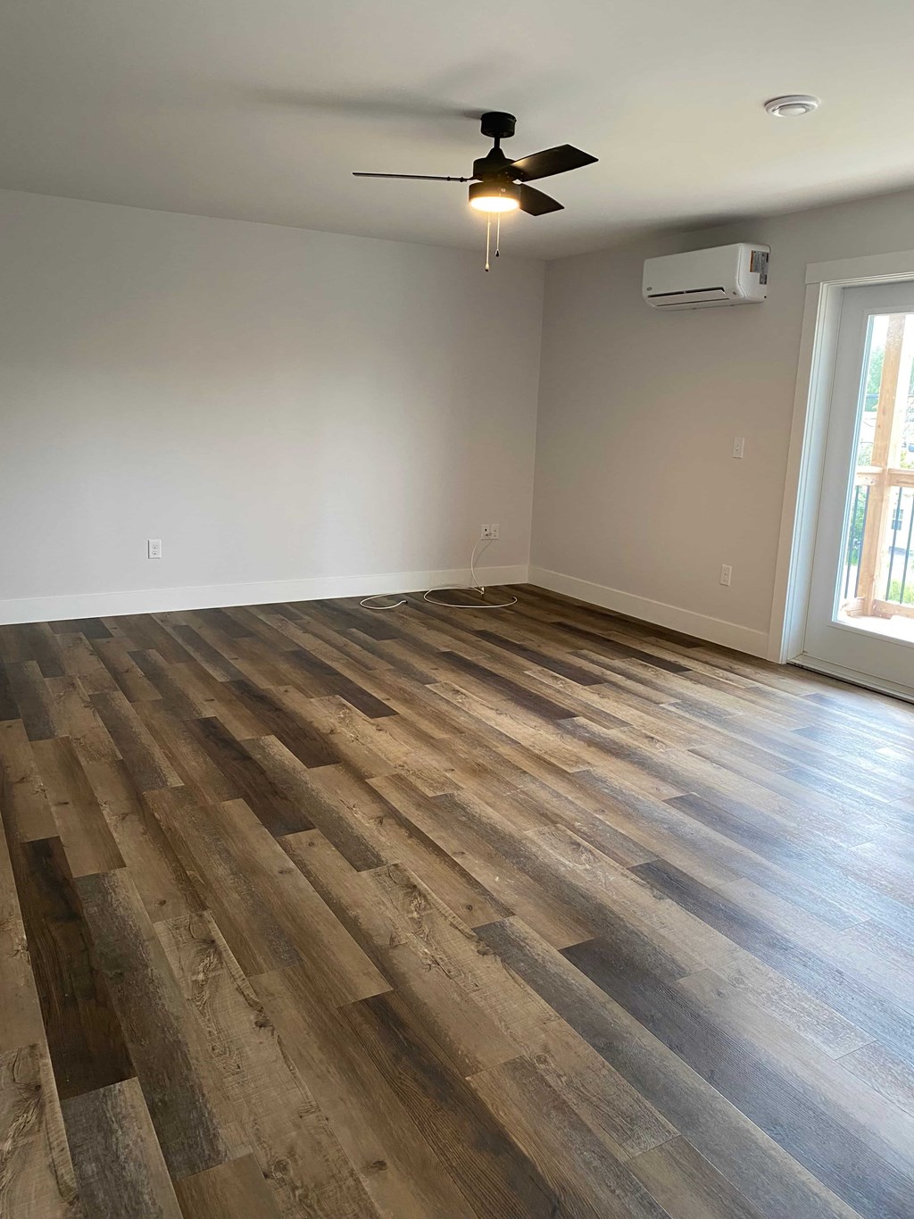 A room with a ceiling fan and wooden flooring.