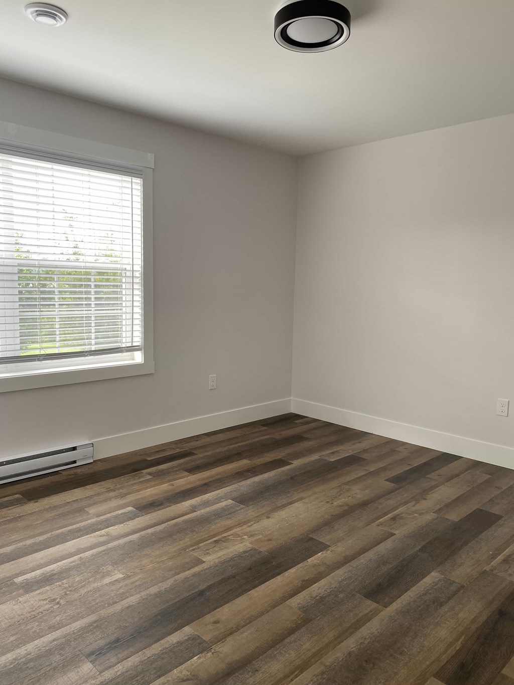 A room with a window and a wooden floor.