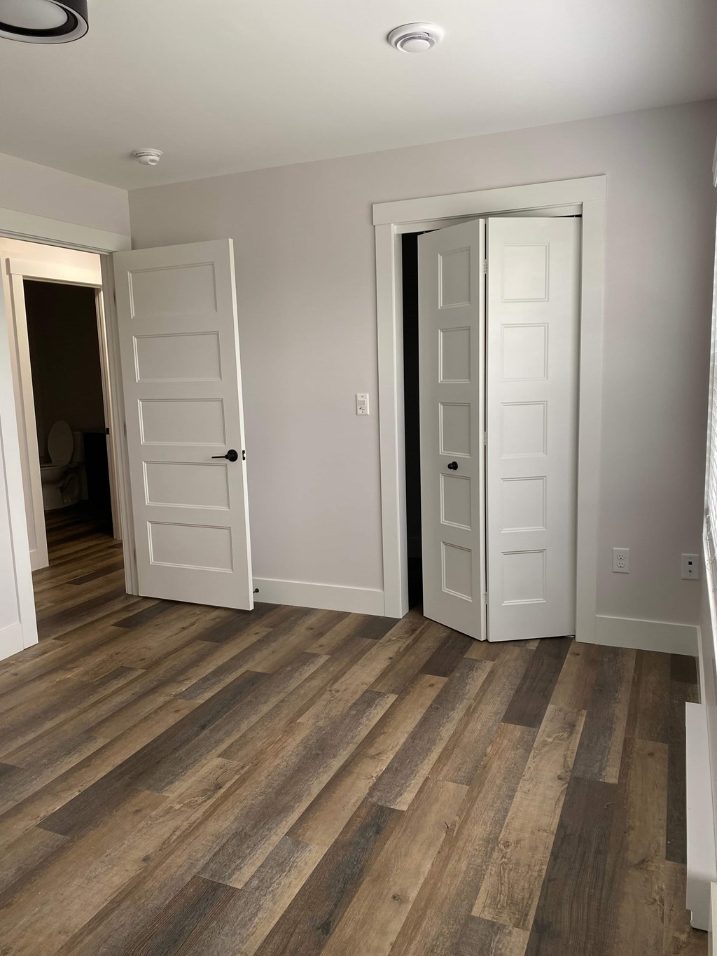 A room with two white doors and wood flooring.