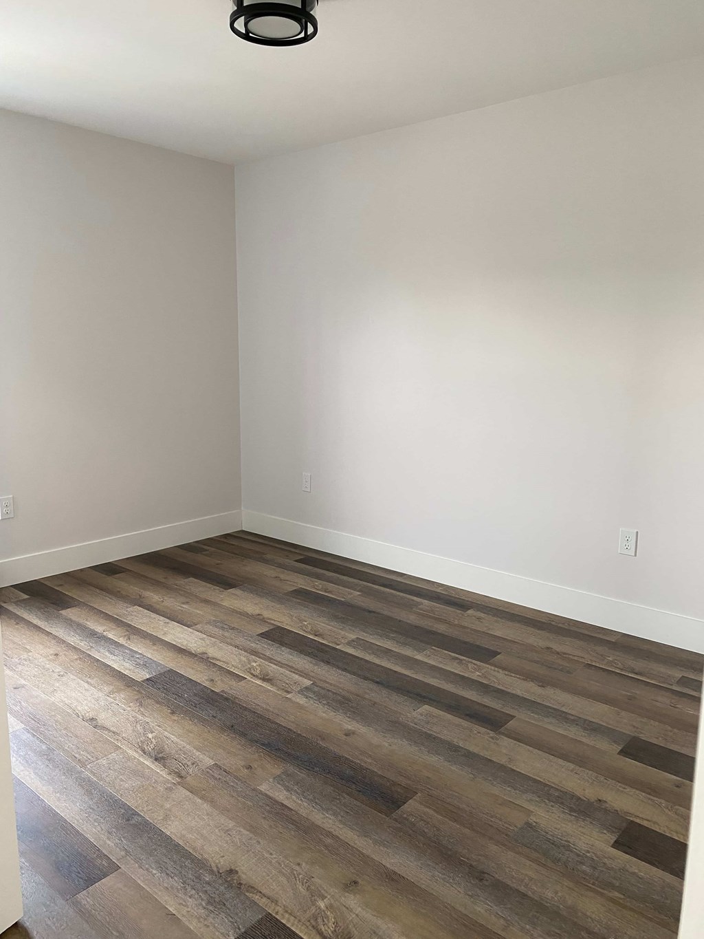 A room with wooden flooring and a ceiling light.