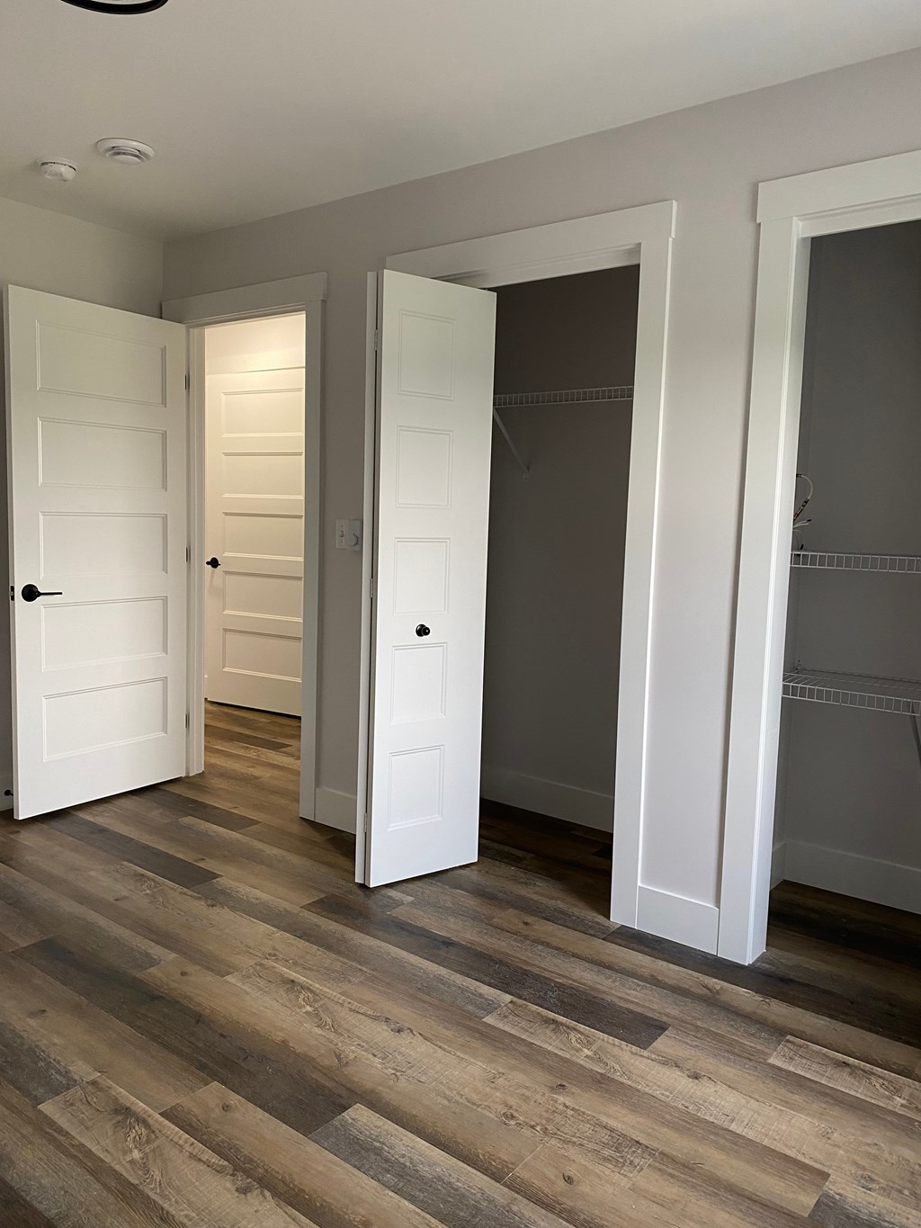 A room with three white doors and wooden floors.