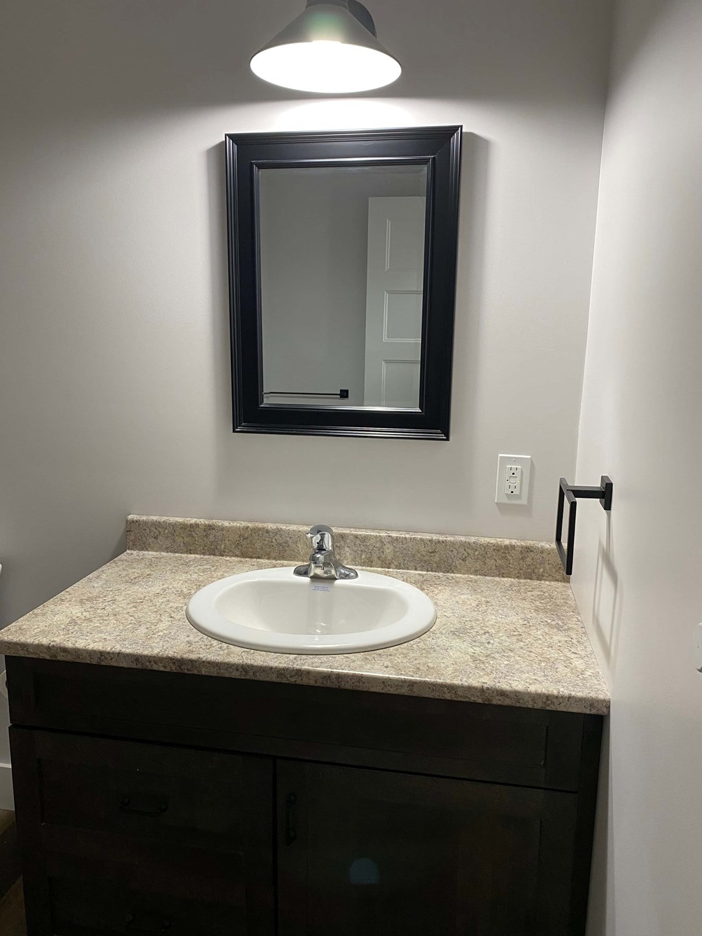 A bathroom sink under a mirror with a light above it.