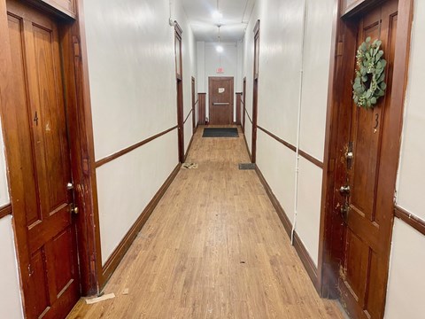A long hallway with doors on both sides and a wreath on the right door.