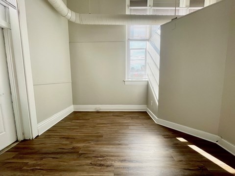 A room with wooden flooring and white walls.