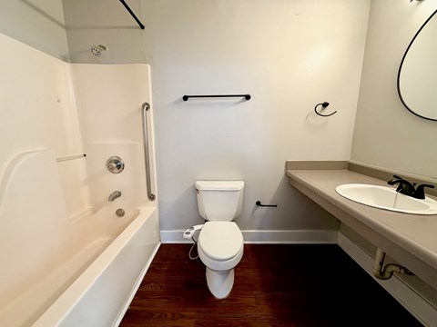 A white toilet sits in a bathroom next to a bathtub and sink.