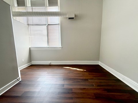 A room with a window and wooden flooring.