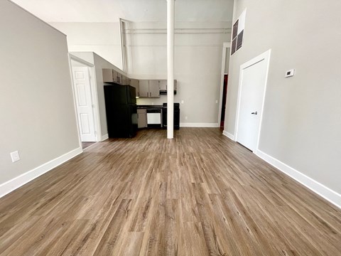 A kitchen area with a black refrigerator and wooden flooring.