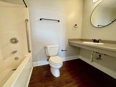 A white toilet in a bathroom with a white bathtub and a white sink.
