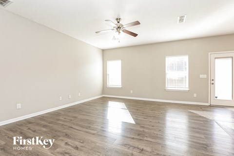 A spacious room with a ceiling fan and wooden flooring.