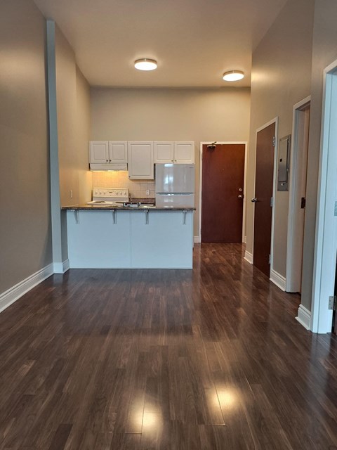A kitchen with white cabinets and a wooden floor.