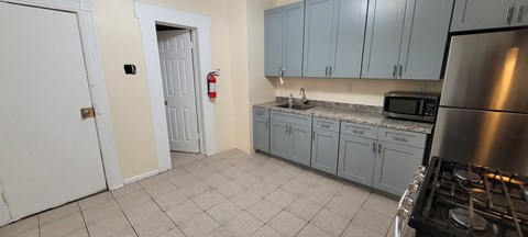 A kitchen with a stove, sink, and cabinets.