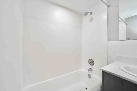 A white bathroom with a tub, sink, and mirror.