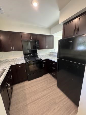 A kitchen with dark wood cabinets and black appliances.