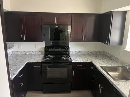 A kitchen with dark brown cabinets and a black stove top oven.