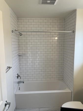 A white bathroom with a white tub and a white toilet.