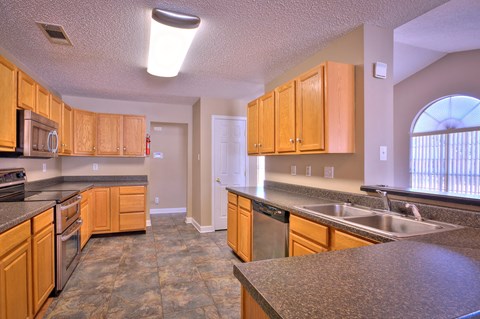A kitchen with wooden cabinets and a tiled floor.
