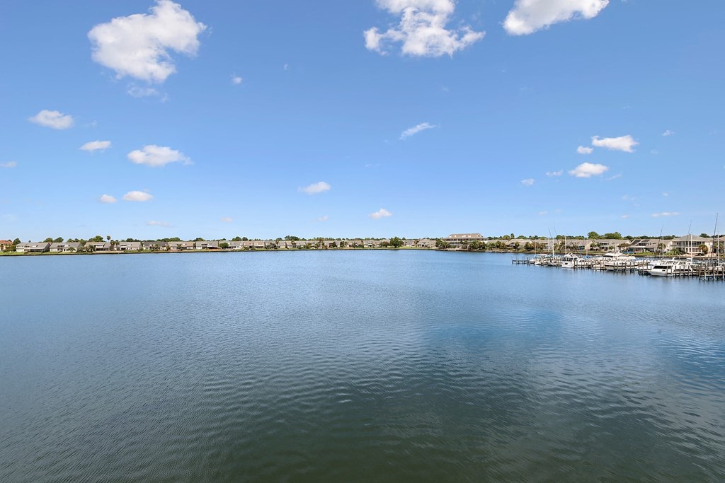 A serene body of water with a dock and boats in the distance under a clear blue sky.
