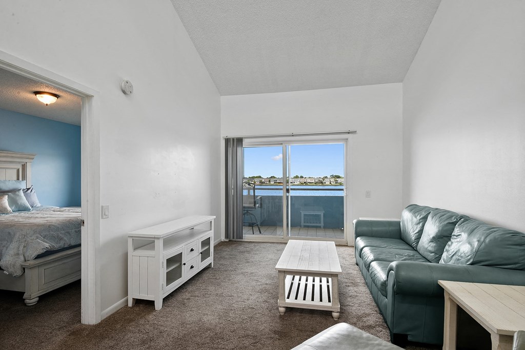 A bedroom with a bed, a couch, and a window overlooking the water.