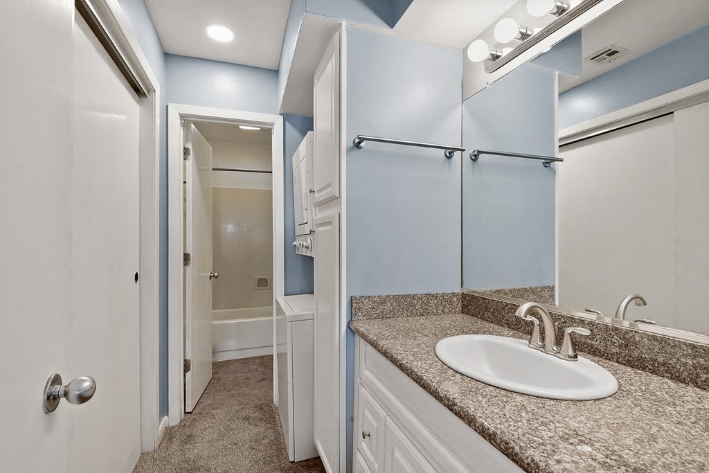 A bathroom with a sink, mirror, and blue walls.